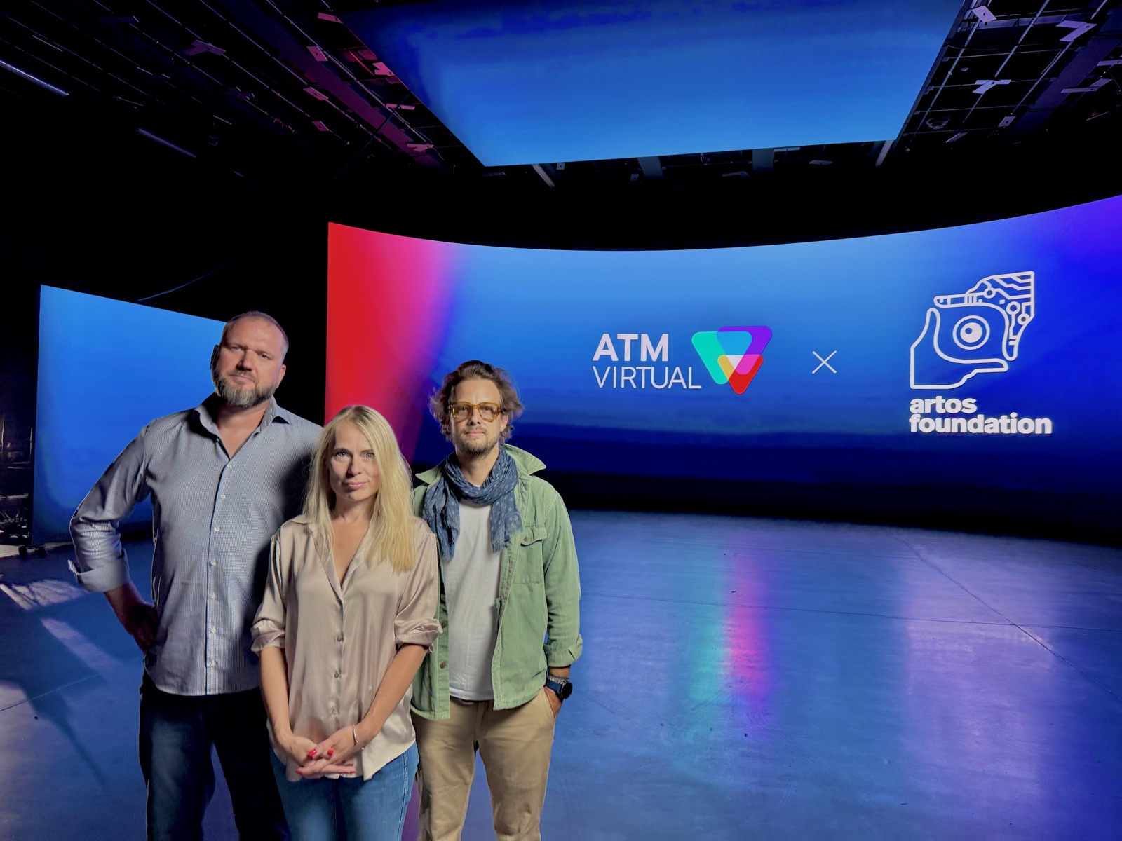 The ARTOS Foundation and ATM Virtual teams in front of ATM Virtual’s curved LED volume wall, which displays the ATM Virtual and ARTOS Foundation partnership lockup.